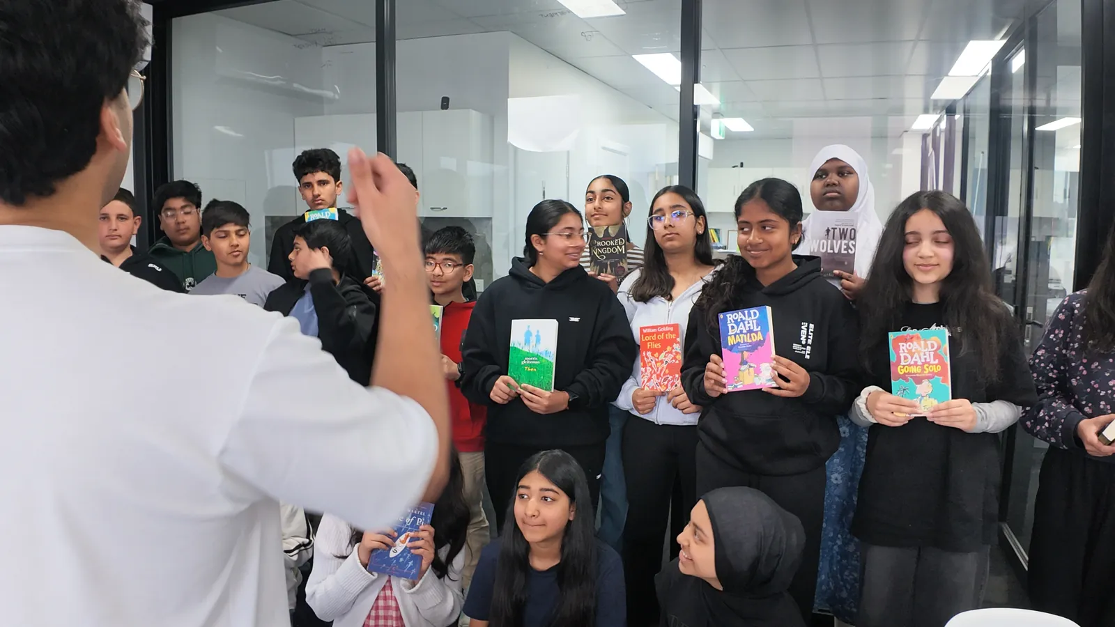 An Aspire tutor leading a reading group discussion with students holding their novels